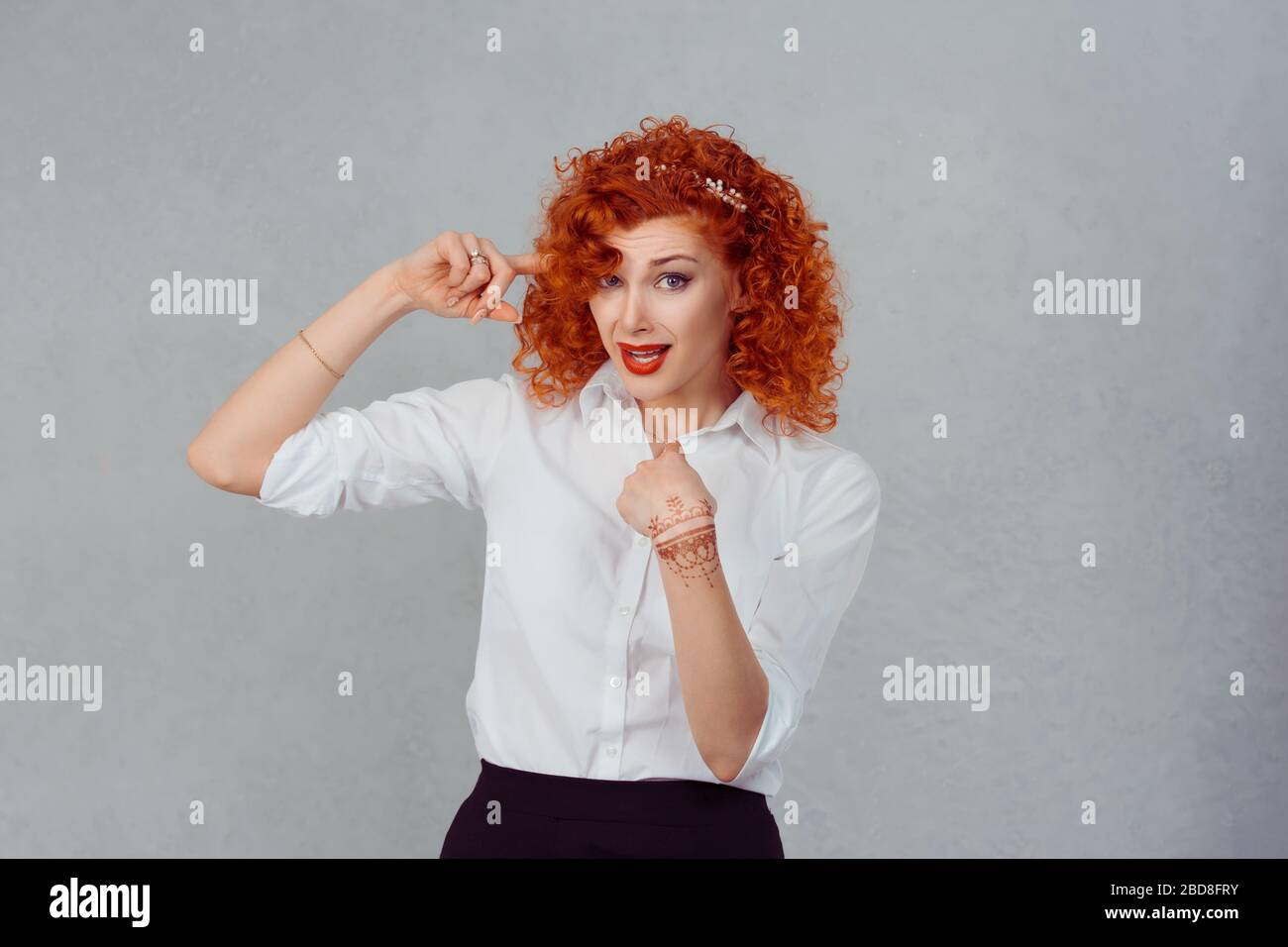 Moi Crazy ? Une femme folle en colère se gestirant avec le doigt contre le temple et l'autre main pointant vers son auto-regardant l'appareil photo dire que je suis fou isolé gris Banque D'Images