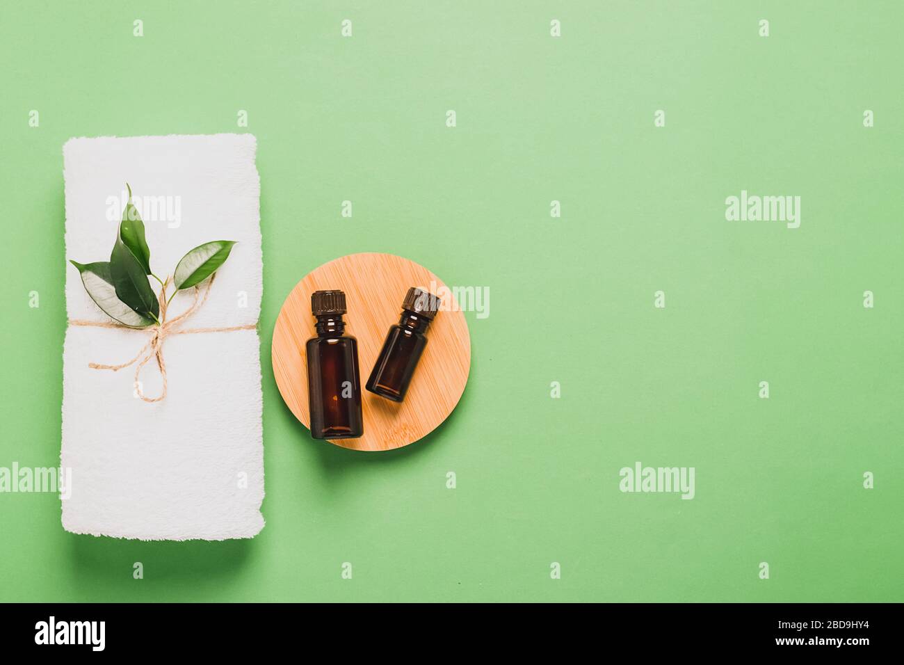 Bouteille d'aromathérapie huile de feuille d'arbre de thé frais serviette blanche douce pour les soins cosmétiques spa pastel vert menthe fond . Banque D'Images