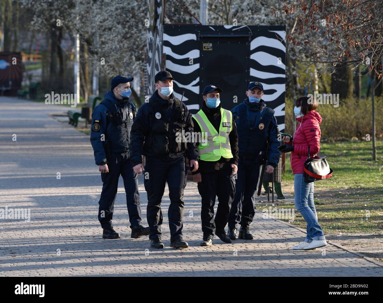 La police et la Garde nationale communiquent des questions à une femme du parc Goloseevsky pendant la pandémie du virus corona. Le Cabinet des ministres de l'Ukraine a adopté une résolution sur le renforcement des mesures de quarantaine. Le gouvernement interdit de se rassembler dans les rues en groupes de plus de deux personnes, en marchant dans les parcs, les zones de parc forestier et les remblais, en visitant les terrains de sport et de jeux. Banque D'Images