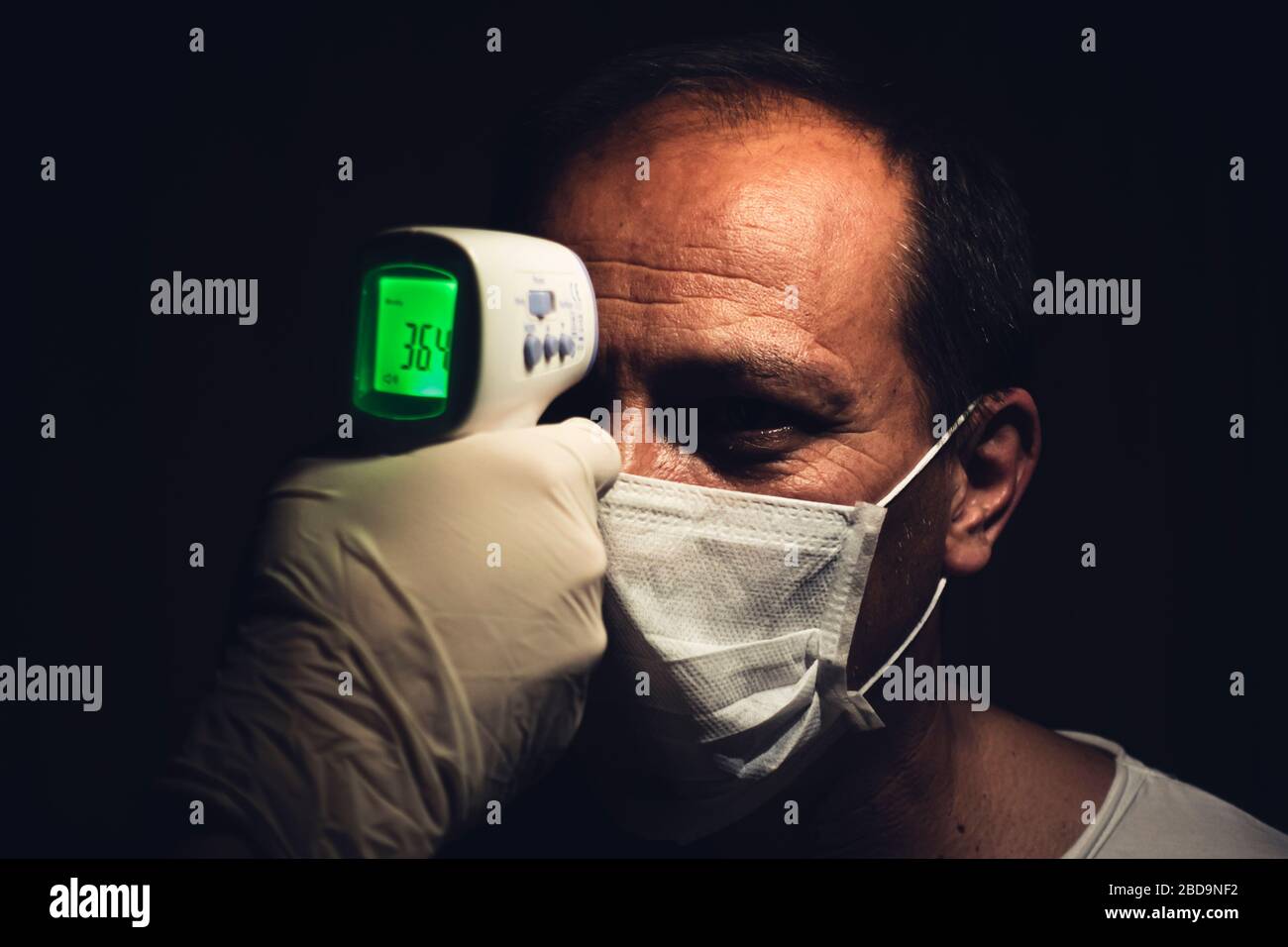Gros plan d'un thermomètre infrarouge mesurant la température corporelle normale d'un homme senior sain pour le coronavirus Banque D'Images