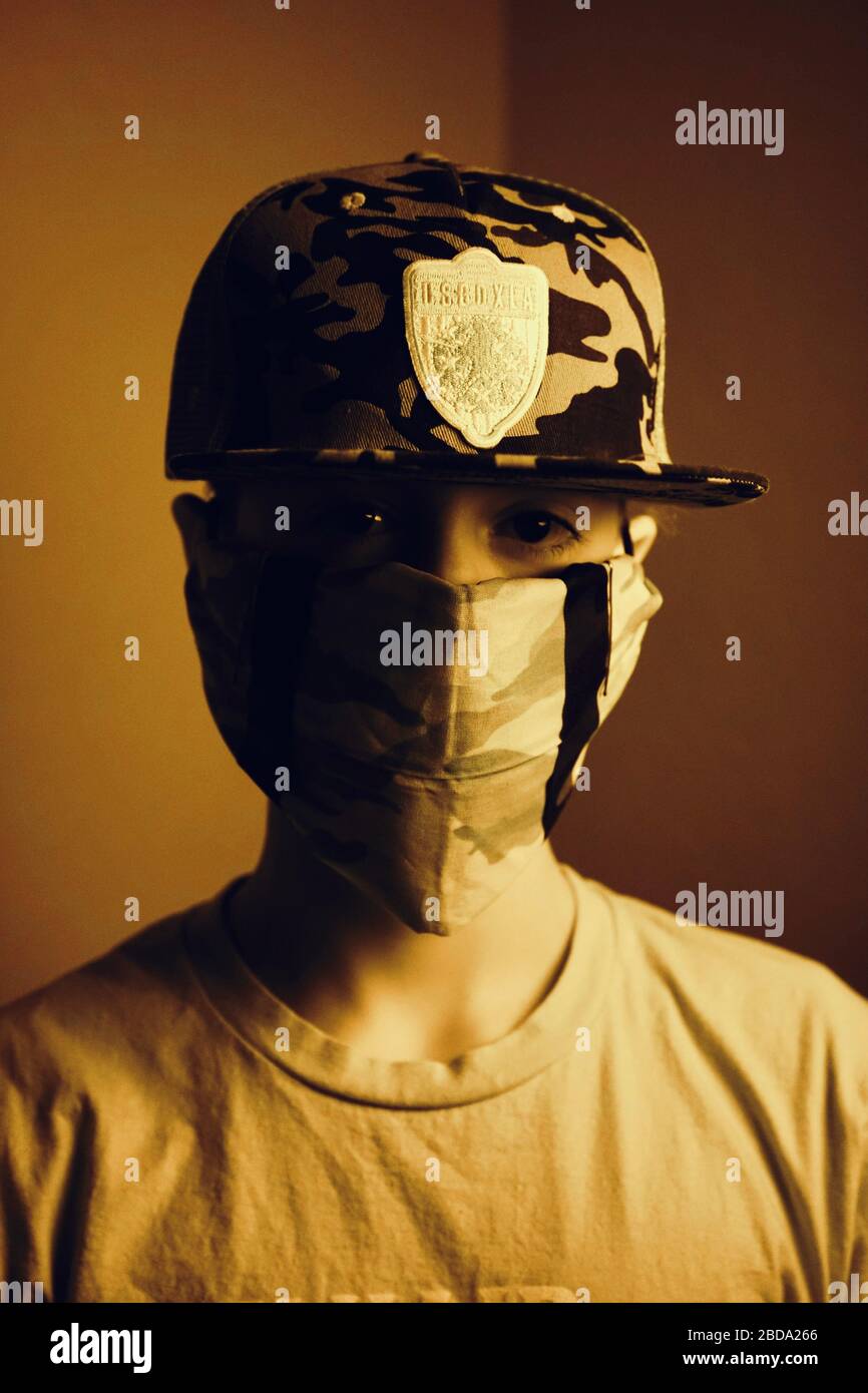 Un adolescent porte un chapeau de camouflage et un masque de camouflage fait  maison à partir d'un bandana Photo Stock - Alamy