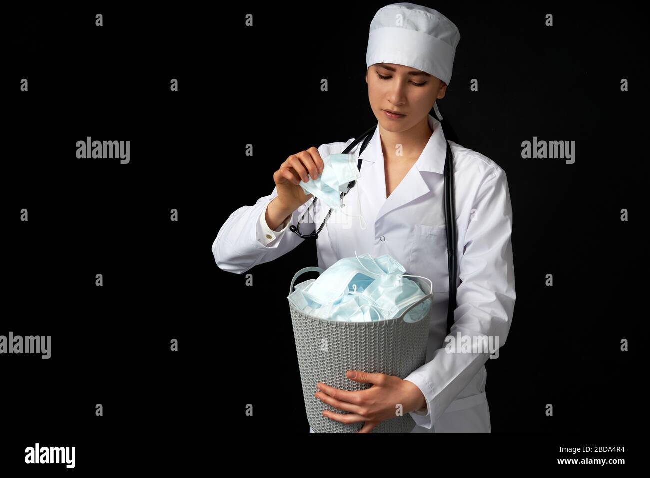 Le médecin tient un seau rempli de masques faciaux usagés, les jetant comme symbole de fin d'épidémie Banque D'Images