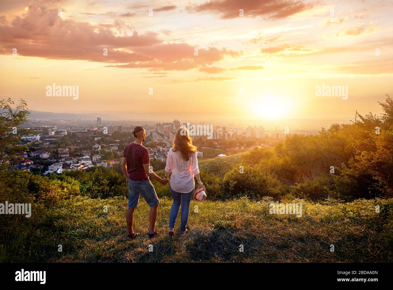 Couple Yong en rose clothes holding par les mains et en regardant le coucher du soleil city Banque D'Images