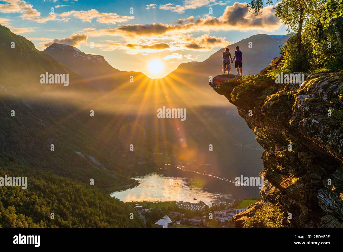 Homme et femme amoureux tenant les mains regardant le village de Geiranger et le Geirangerfjord au coucher du soleil, plus og Romsdal comté, Norvège Banque D'Images