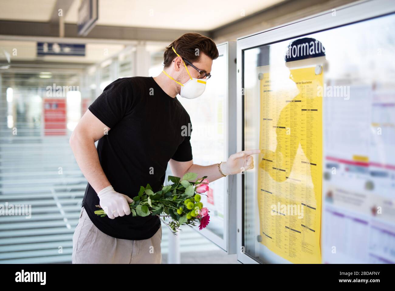 Un homme prend quelqu'un à la gare dans une ère de virus corona avec un masque respiratoire et des gants en caoutchouc Banque D'Images