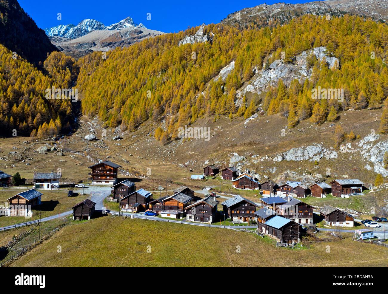 Le hameau de Satarma au pied d'une forêt de mélèze aux couleurs vives de l'automne, Val d'Herens, Eringertal, Valais, Suisse Banque D'Images