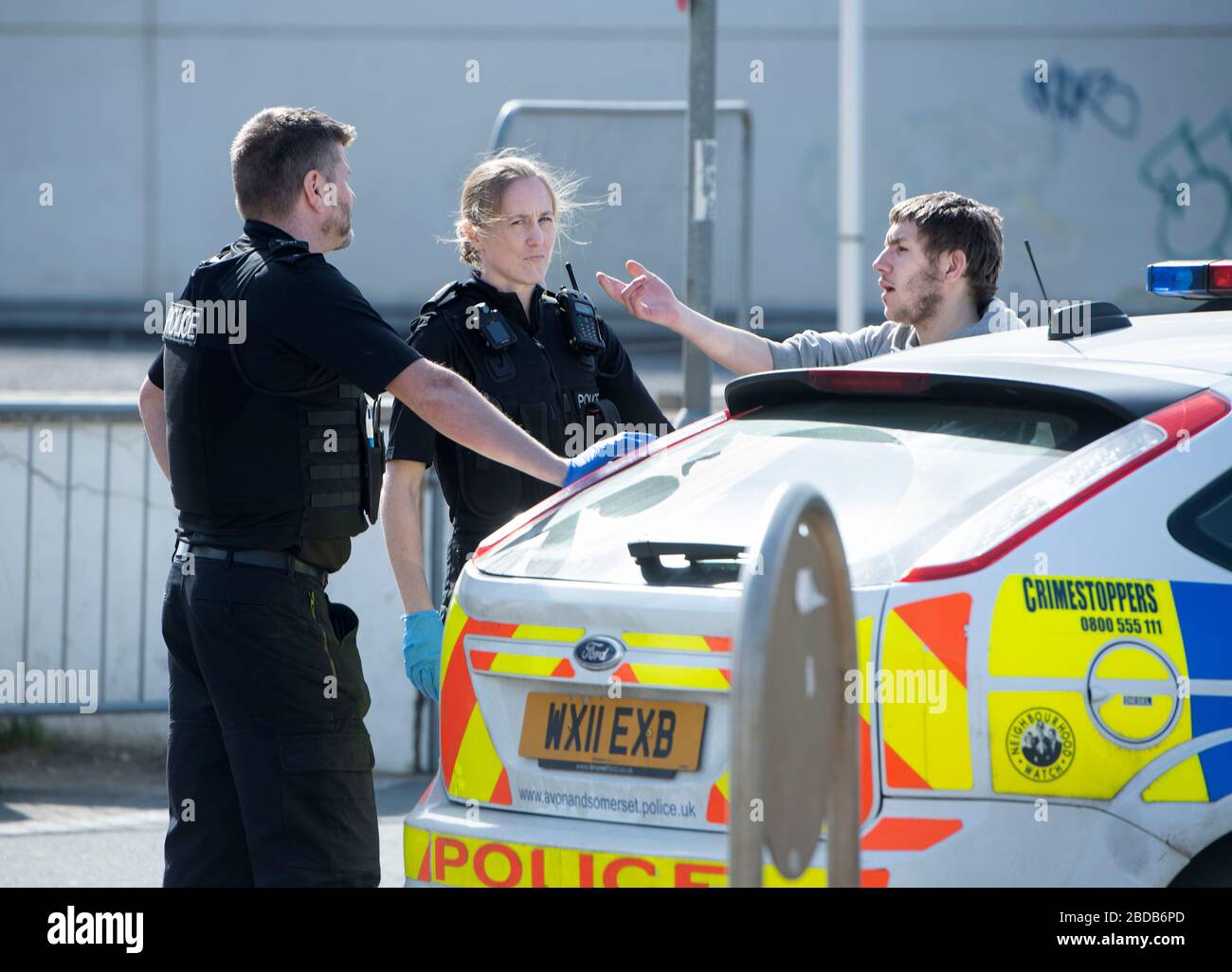 Une patrouille de police négocie avec un homme et le met dans une voiture de patrouille à Weston-super-Mare pendant le verrouillage de Coronavirus Banque D'Images