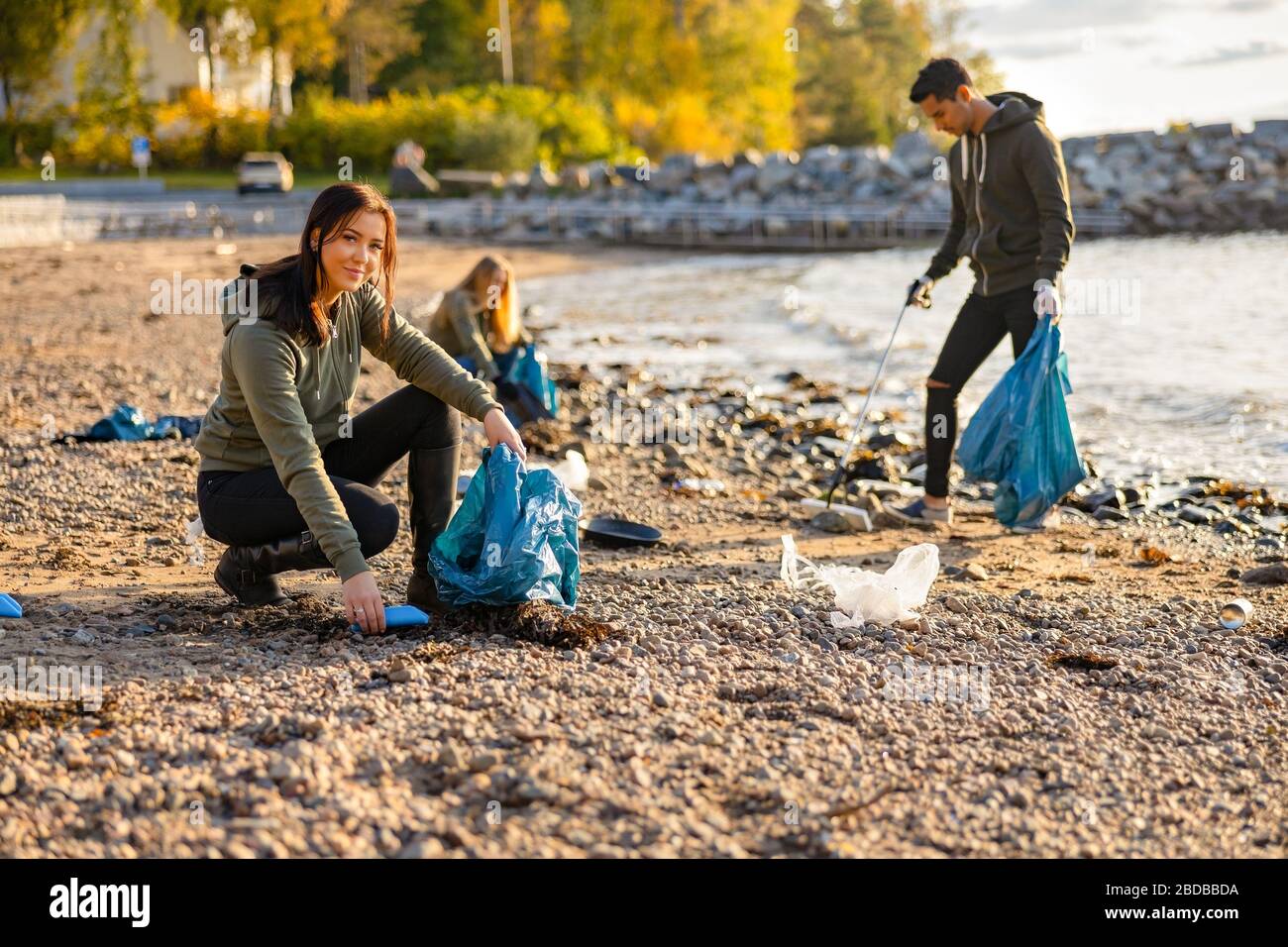 Jeune femme ramassant les déchets en sac at beach Banque D'Images