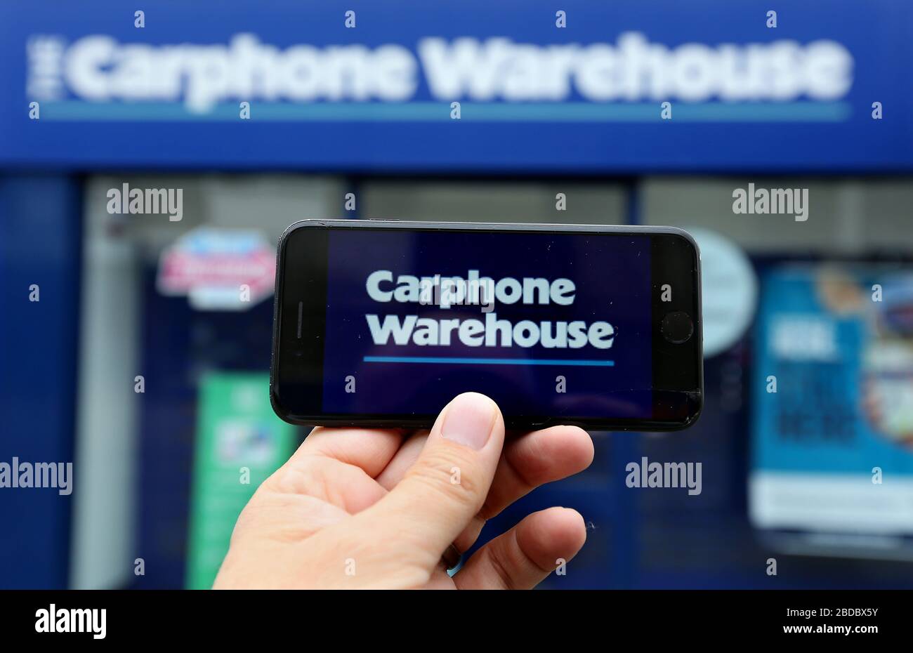 Une image générique du logo Carphone Warehouse sur un smartphone avec la boutique visible derrière. Banque D'Images