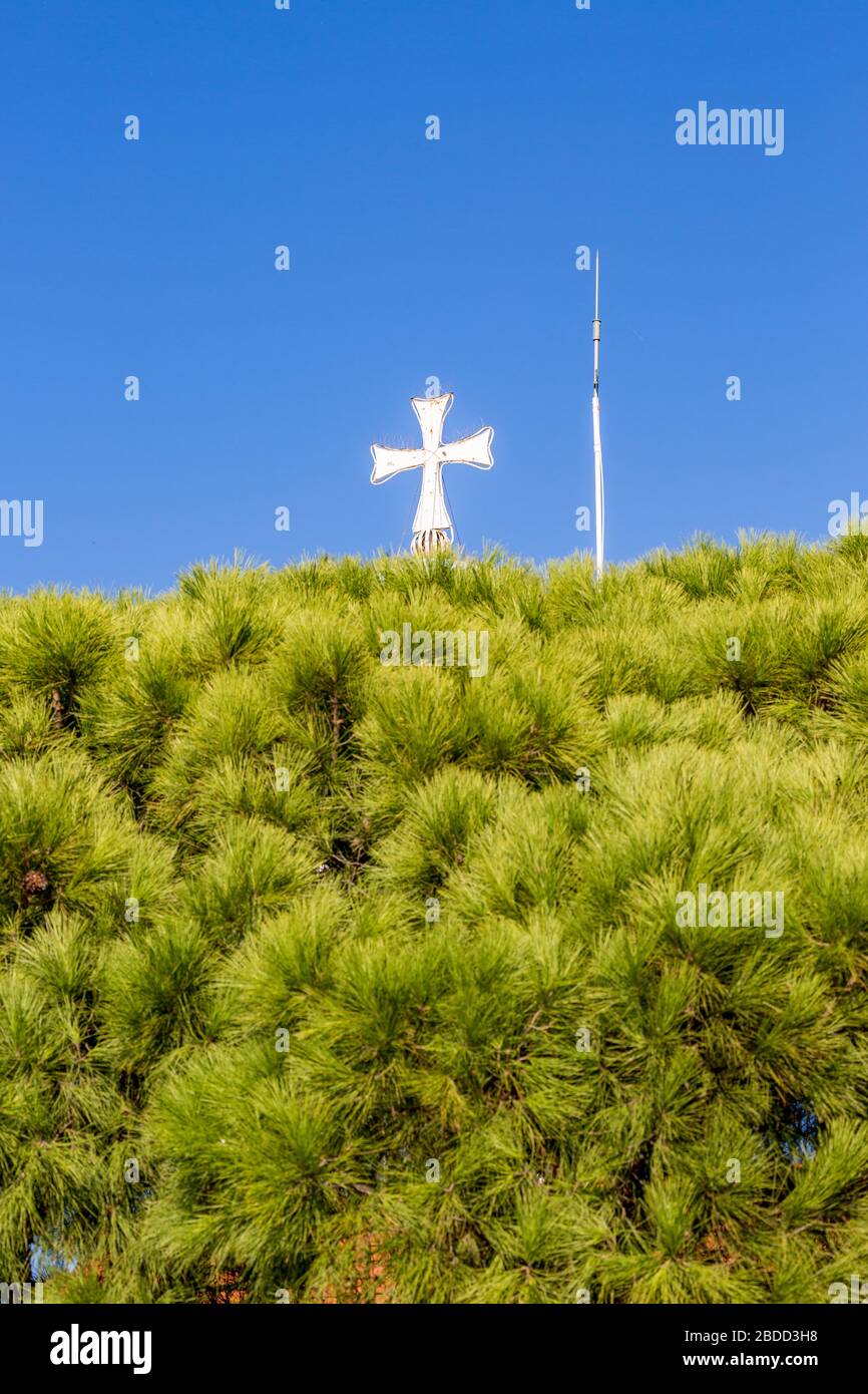 Belle croix blanche de l'église orthodoxe du Monastère de Saint-Nicolas, lac de Vistonida, Porto Lagos, région de Xanthi, nord de la Grèce, clocher vue partielle contre ciel bleu clair, arbres verts Banque D'Images