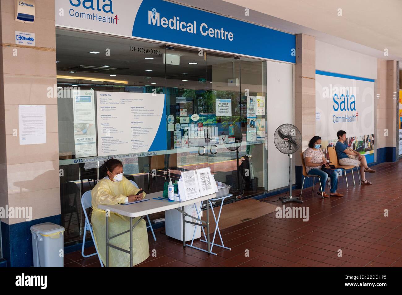 28.02.2020, Singapour, , Singapour - un employé est assis devant le centre médical SATA CommHealth dans le district d'Ang Mo Kio et porte un respir Banque D'Images