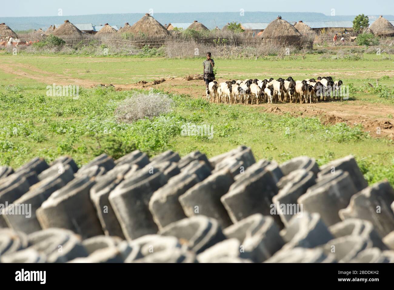 14.11.2019, Gode, région somalienne, Ethiopie - tuyaux d'eau en béton empilés pour l'approvisionnement en eau potable. En arrière-plan le village Burferedo et un garçon Banque D'Images