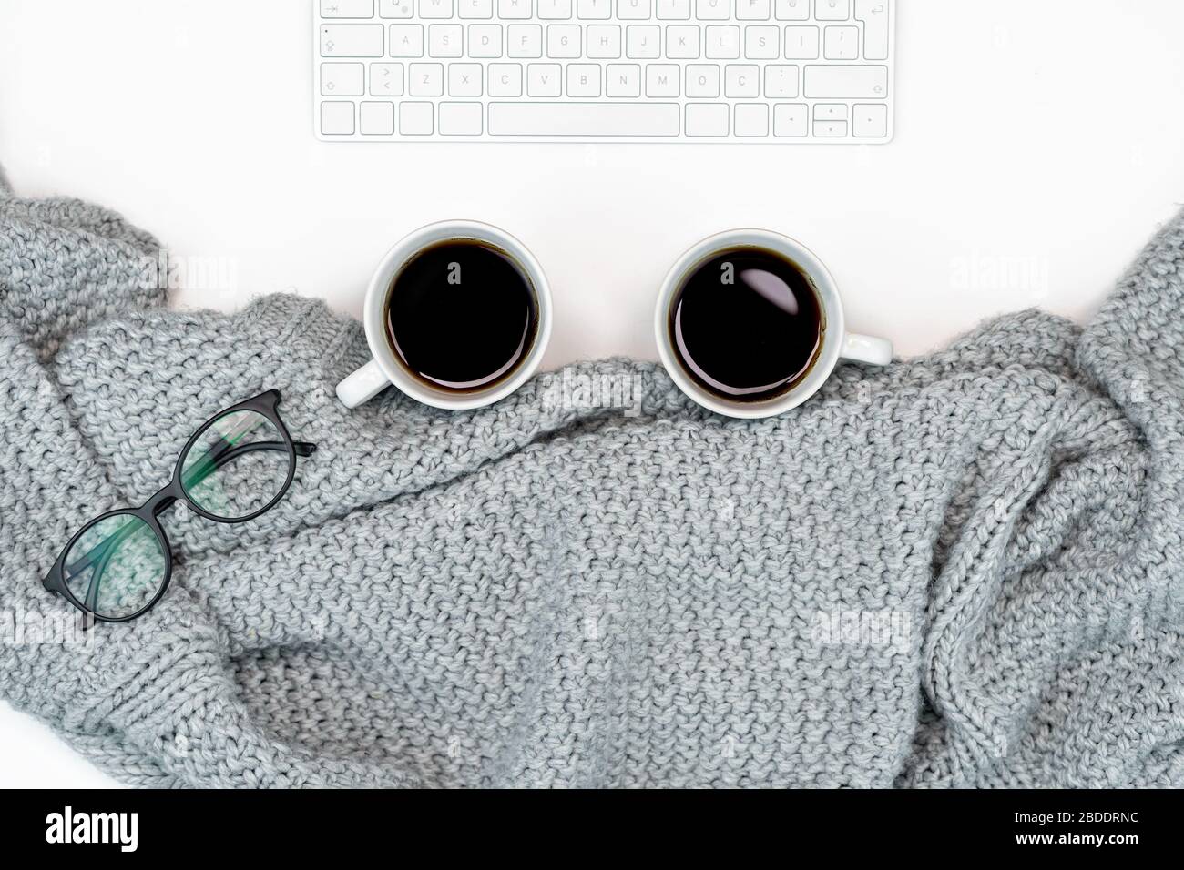 Un espace de travail confortable pour écrire ou regarder un film avec un pull chaud et 2 tasses de café, un ordinateur portable de travail à la maison. Écriture. Concept chaud pour le bien-être Banque D'Images