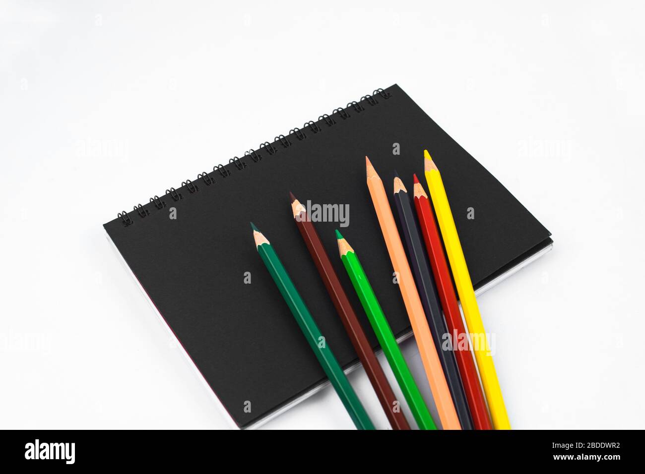 Différents crayons de couleur au crayon dispersés sur un journal isolé en papier noir Banque D'Images