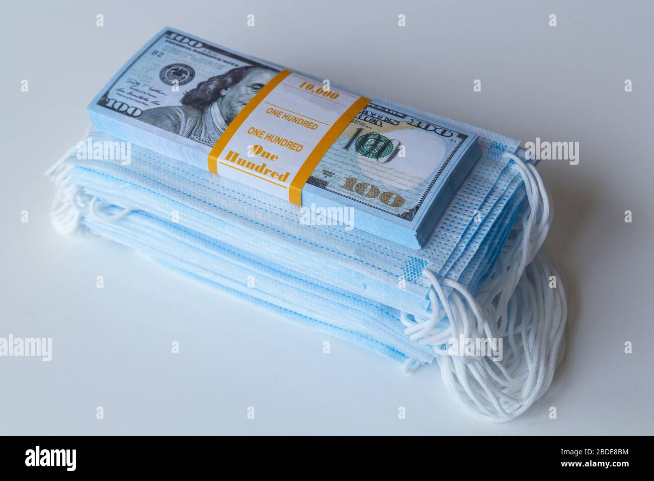 Un paquet de masques médicaux et une pile de 100 dollars facture comme un symbole de prix plus élevés et un insuffisance dans la protection des voies respiratoires de Banque D'Images