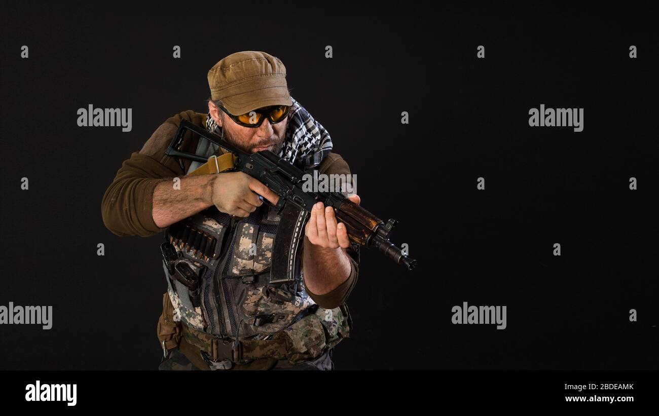 Soldat mercenaires avec un pistolet visant l'ennemi. Photo sur fond sombre. Concept moderne d'armée privée. Banque D'Images