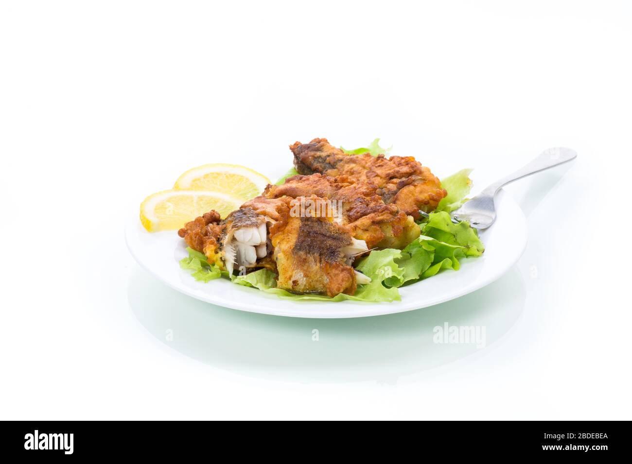 poisson frits hake dans la pâte avec laitue et citron dans une plaque isolée sur fond blanc Banque D'Images