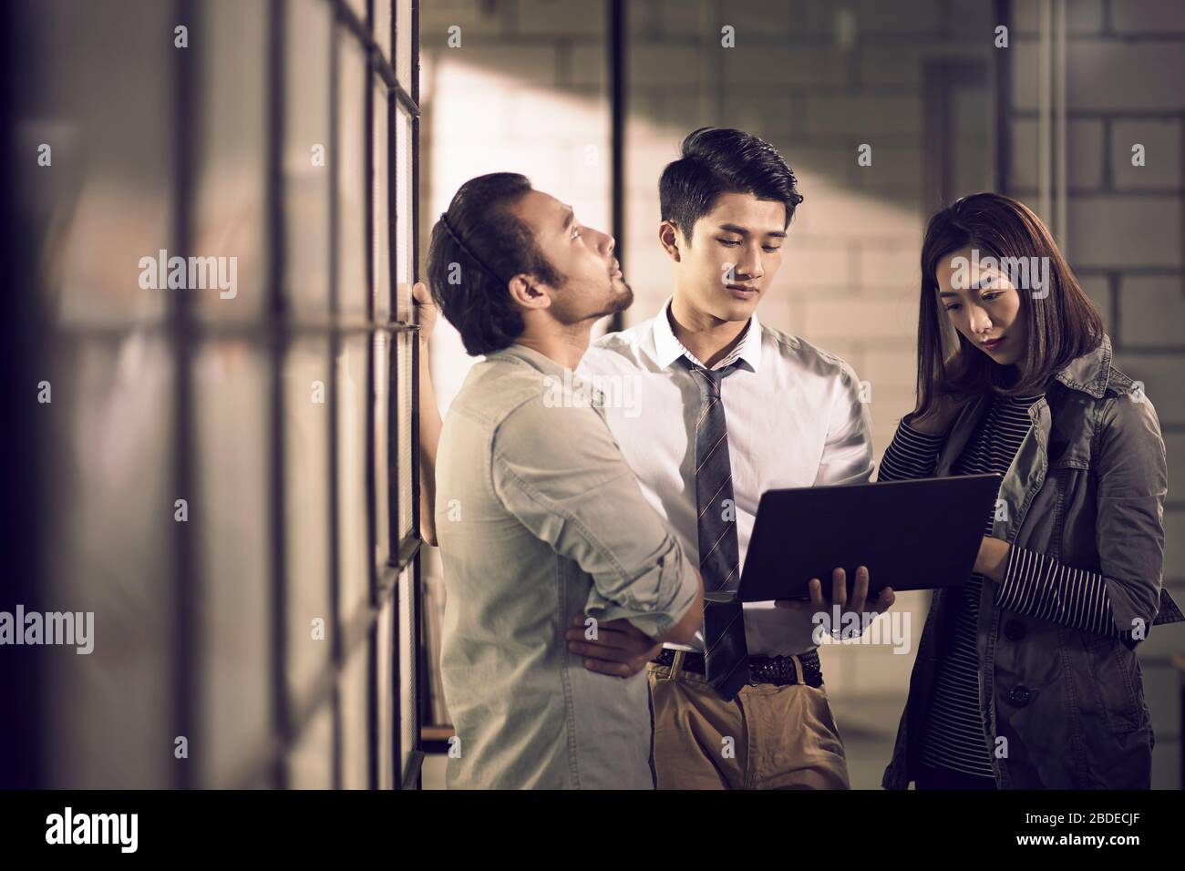 équipe de trois jeunes entrepreneurs asiatiques se réunissent au bureau avec une discussion utilisant un ordinateur portable au bureau Banque D'Images