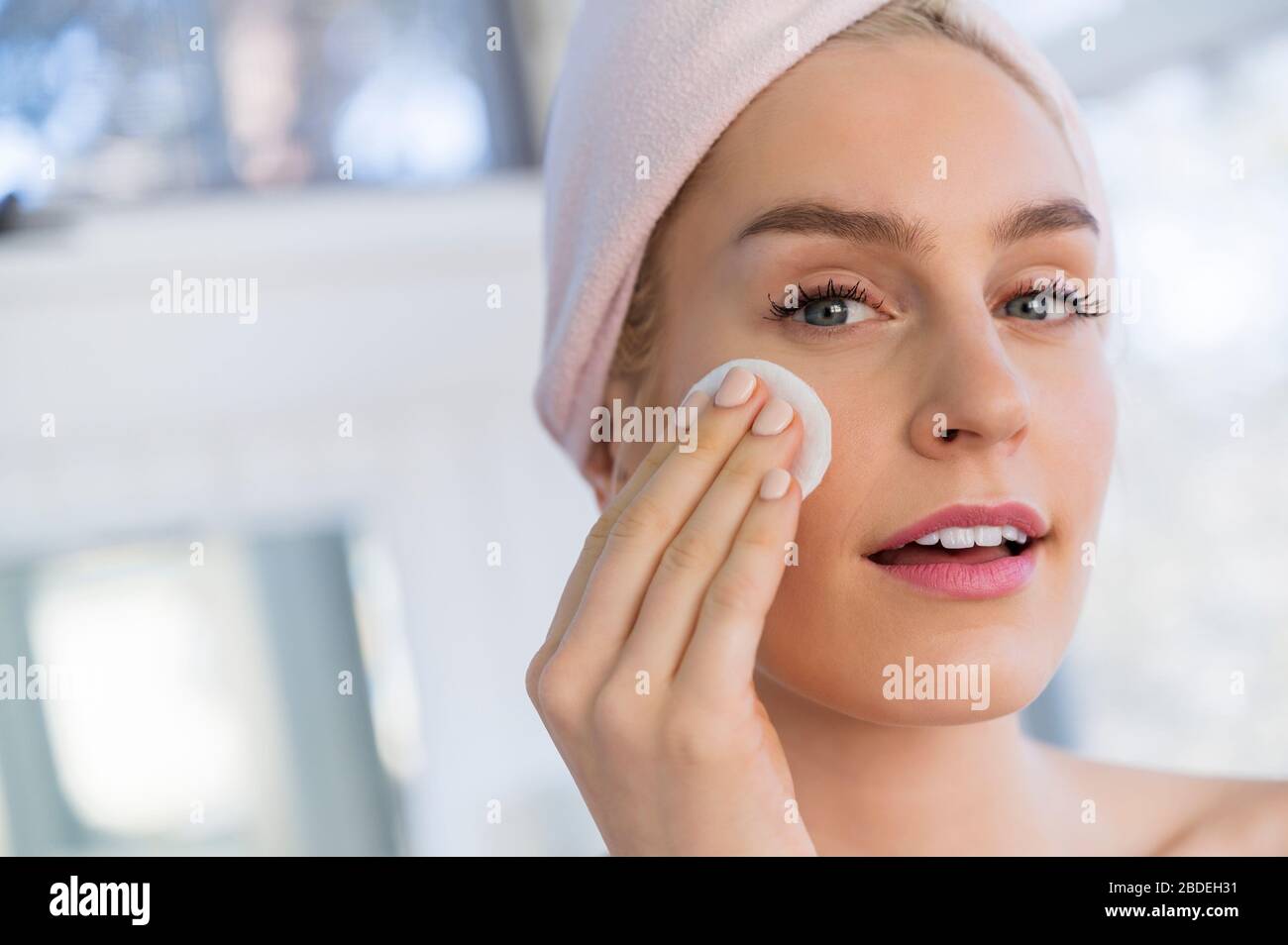 Femme utilisant un tampon de nettoyage pour laver le visage Banque D'Images