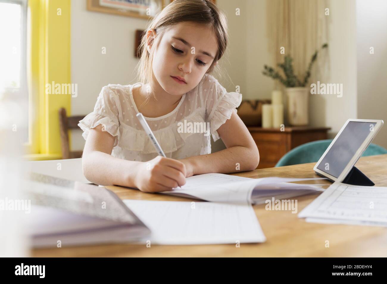 Fille (6-7)Â travaillant sur le travail scolaire à la maison Banque D'Images