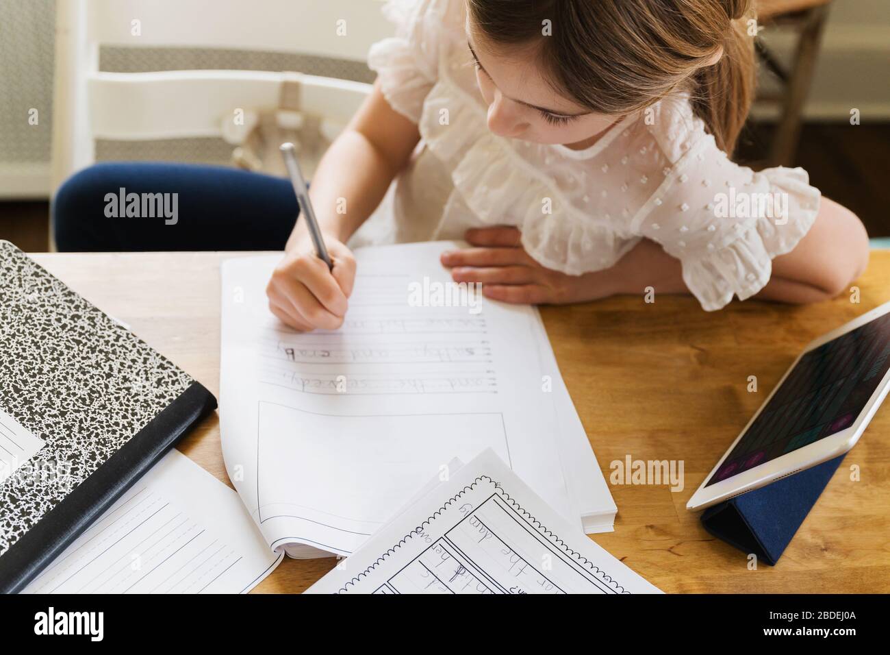 Fille (6-7)Â travaillant sur le travail scolaire à la maison Banque D'Images