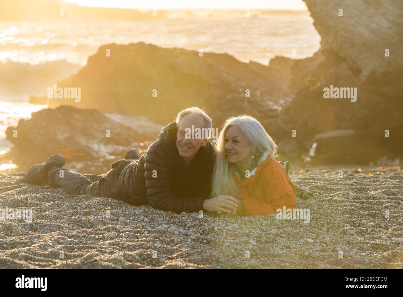 Couple de Séno profitant du coucher de soleil sur la plage Banque D'Images