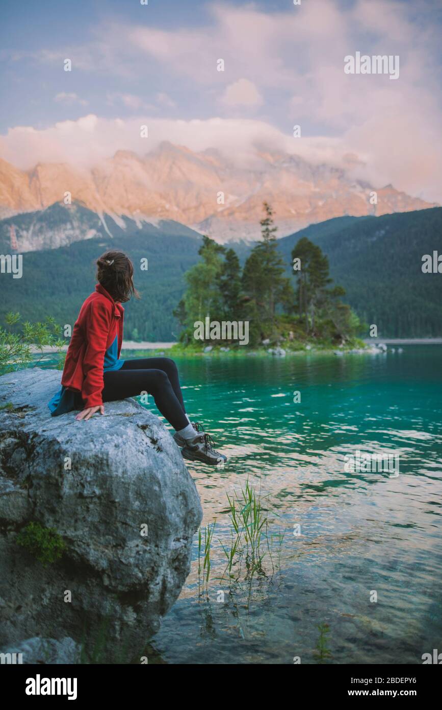 Allemagne, Bavière, Eibsee, jeune femme assise sur le rocher et regardant la vue panoramique par le lac EibseeÂ dans les Alpes bavaroises Banque D'Images