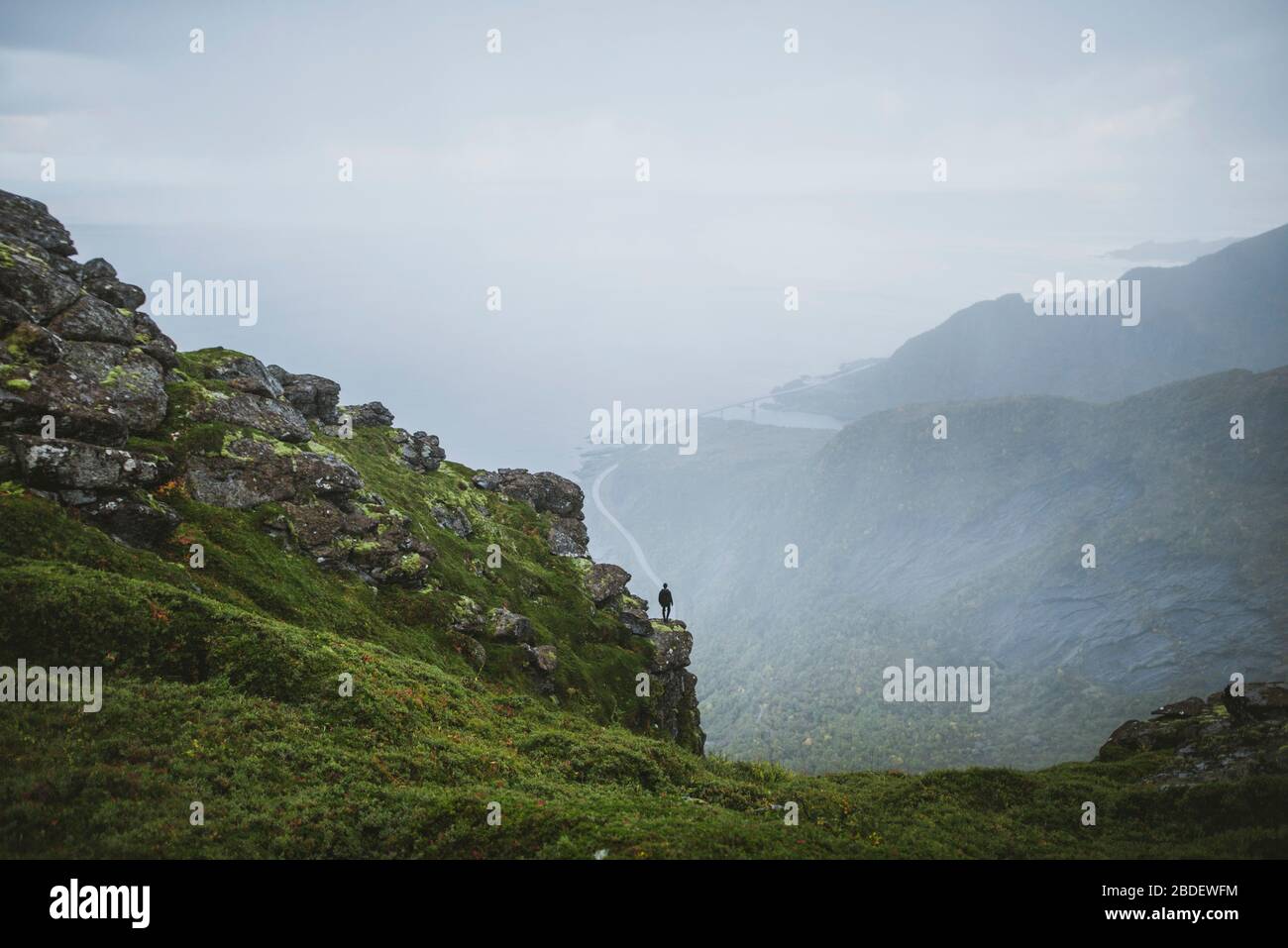 Norvège, îles Lofoten, Reine, Homme regardant la vue depuis la montagne ReinebringenÂ pendant la pluie Banque D'Images