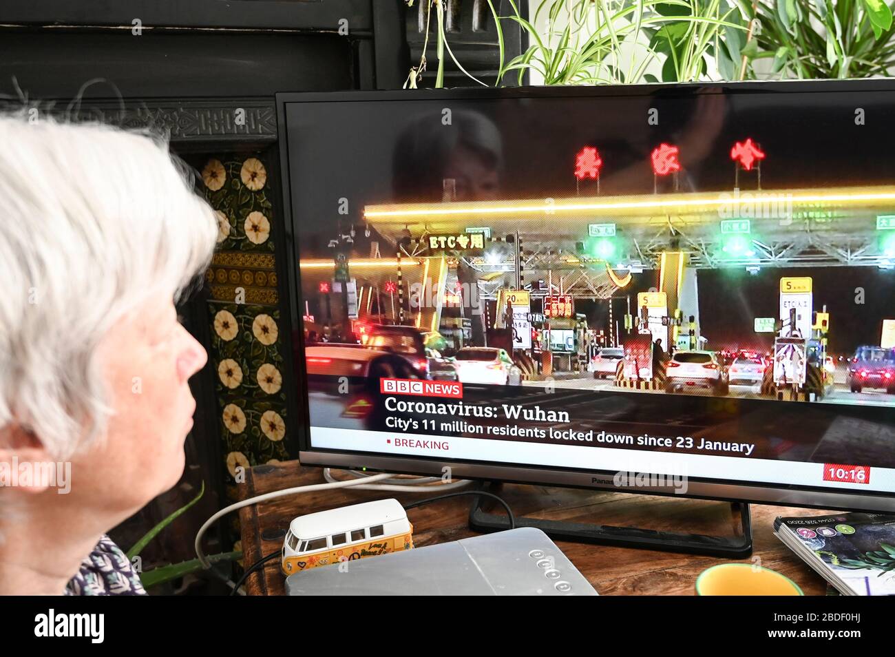 Une femme regardant les nouvelles de la BBC avec des développements à Wuhan, Chine concernant Covid-19 et le verrouillage. Banque D'Images