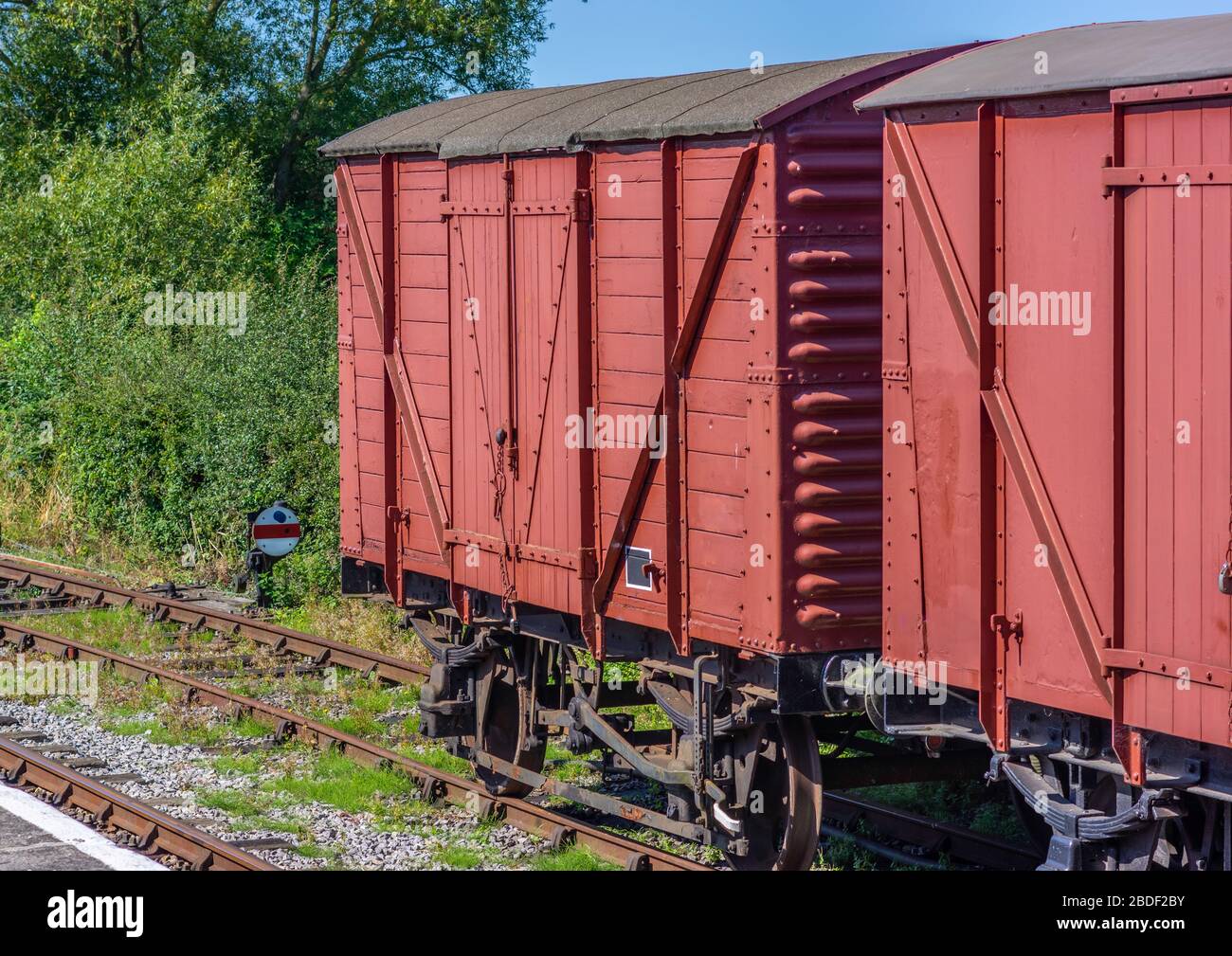 Deux wagons de marchandises rouges à l'ancienne ont misé sur une voie d'évitement lors d'une journée ensoleillée. Banque D'Images