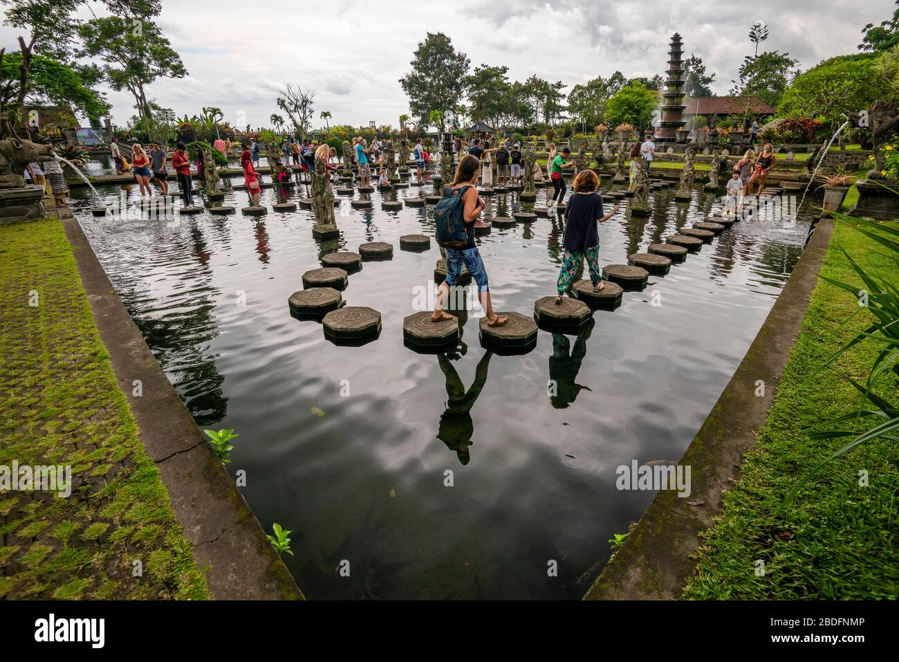 Vue horizontale des touristes marchant sur les pierres de pas au palais d'eau de Tirta Gangga à Bali, Indonésie. Banque D'Images