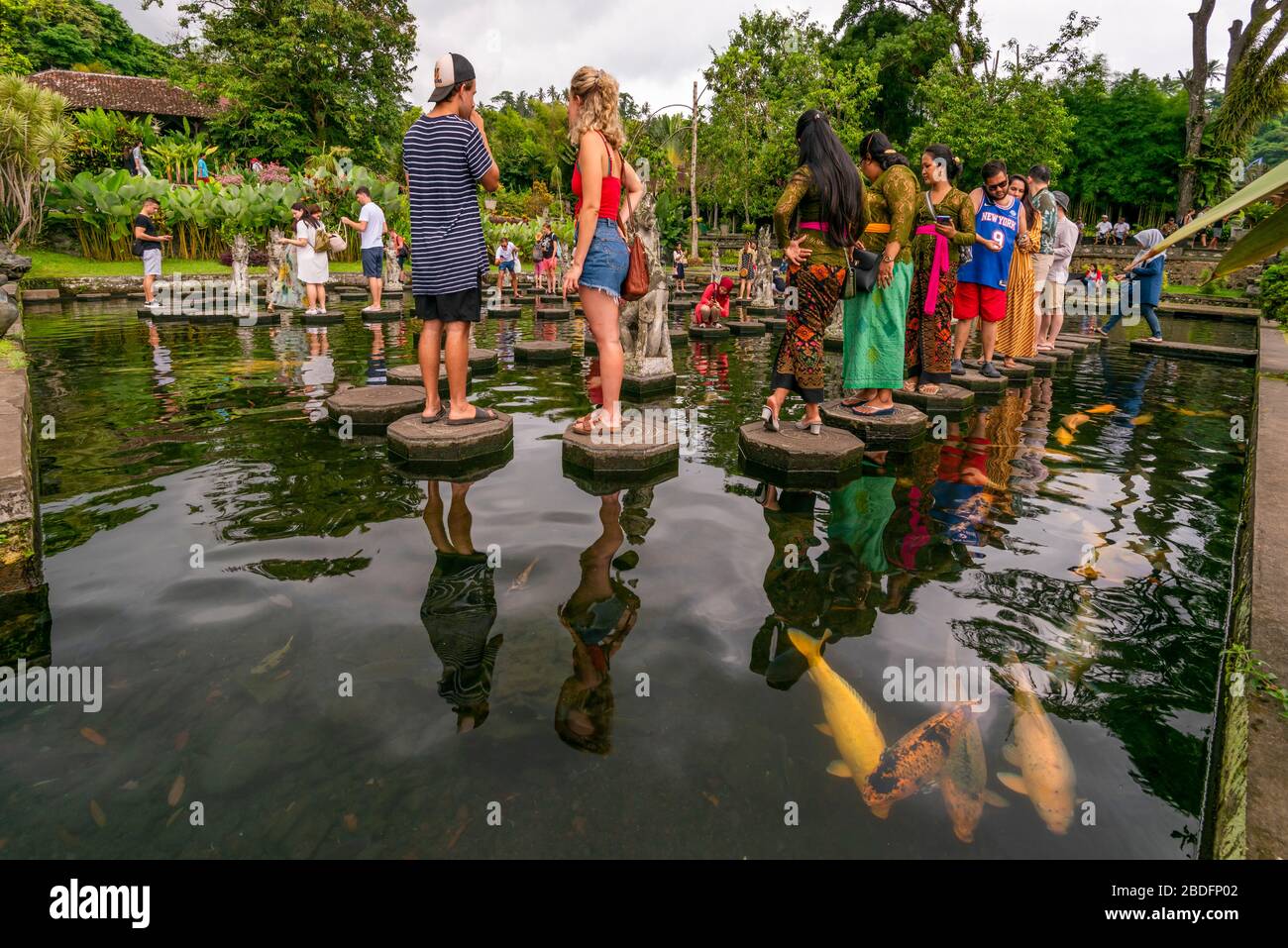 Vue horizontale des touristes marchant sur les pierres de pas au palais d'eau de Tirta Gangga à Bali, Indonésie. Banque D'Images