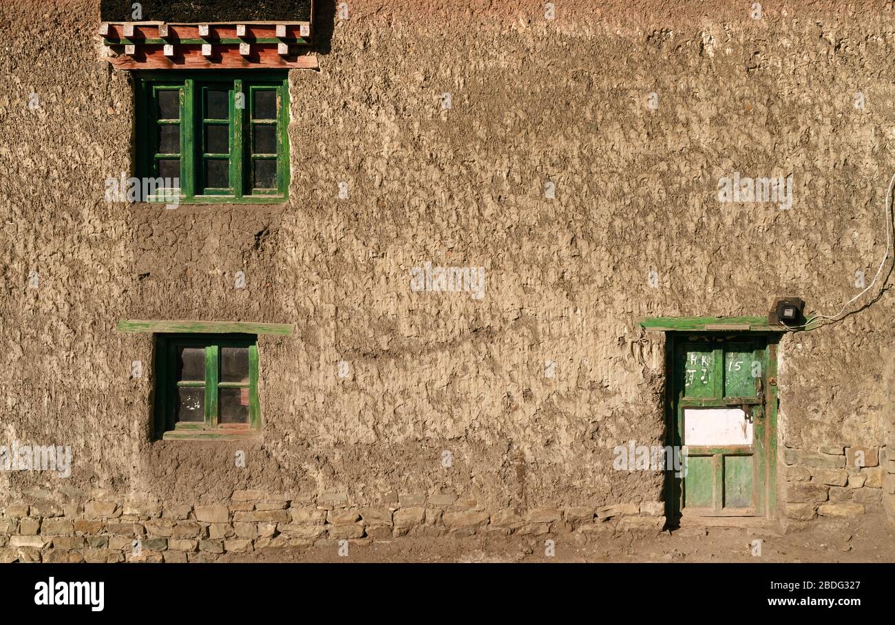 Maison de village traditionnelle en boue avec fenêtres encadrées en bois et porte sur une matinée ensoleillée en été à KKomic, Himachal Pradesh, Inde. Banque D'Images