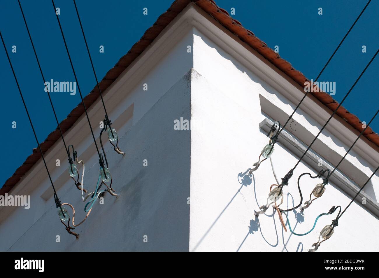 câbles de distribution d'électricité fixés à la façade d'une sous-station avec isolants en verre au soleil Banque D'Images
