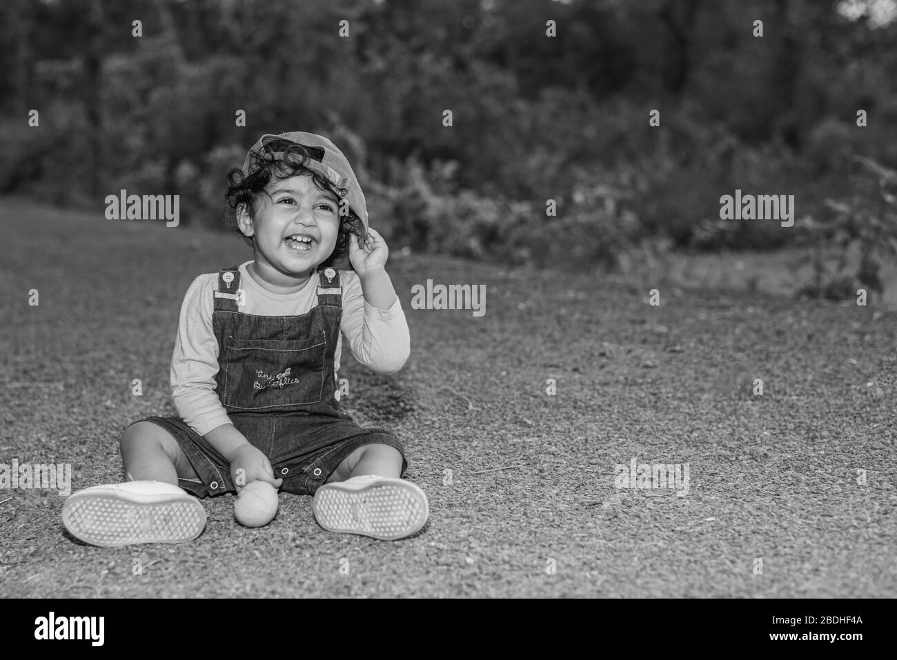 Margao Goa India 2 Avril Enfant Bebe De Jolie Fille Indienne Ludique Portant Une Casquette Lisant Un Livre Et Jouant Ayant Des Champs Et Le Coucher De Soleil Dans L Arriere Photo
