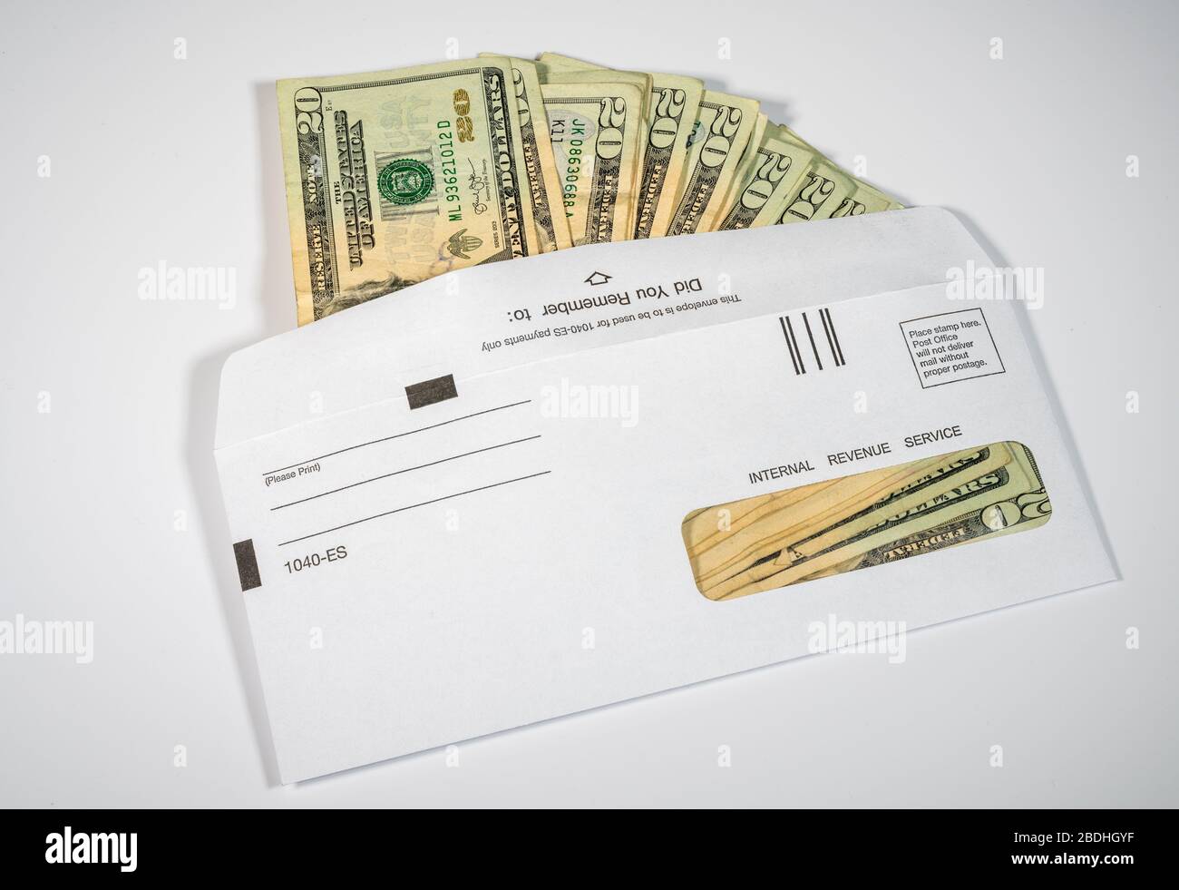 Pile de billets de 20 dollars dans l'enveloppe de l'IRS pour illustrer le paiement de relance du coronavirus ou l'estimation des paiements fiscaux sur fond blanc Banque D'Images