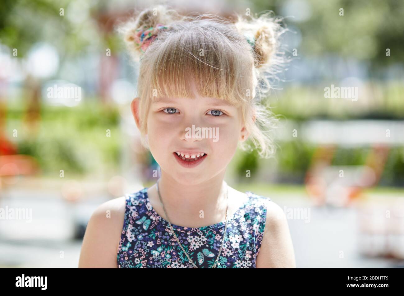 Adorable enfant en robe se posant à l'extérieur. La jeune fille caucasienne bénéficie d'un style de vie lumineux d'été ou de printemps Banque D'Images