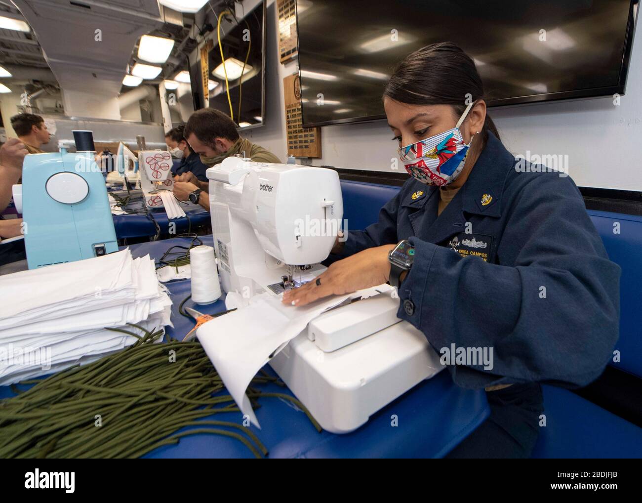 Marins de la marine américaine, tissus coupés pour masques en tissu à bord du destroyer USS Kidd de missile guidé de classe Arleigh Burke 6 avril 2020 dans le Pacifique oriental. Les marins sont maintenant tenus de porter des masques lorsque la distanciation sociale peut ne pas être possible pour aider à atténuer la propagation et empêcher COVID-19. Banque D'Images