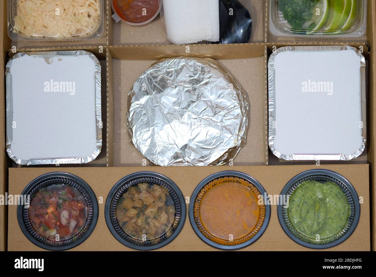 Boîte en carton avec récipients en plastique remplis de nourriture.  Livraison de nourriture maison dans la vaisselle jetable. Emballer la  nourriture pour la livraison à partir d'un café. Le mexicain à emporter