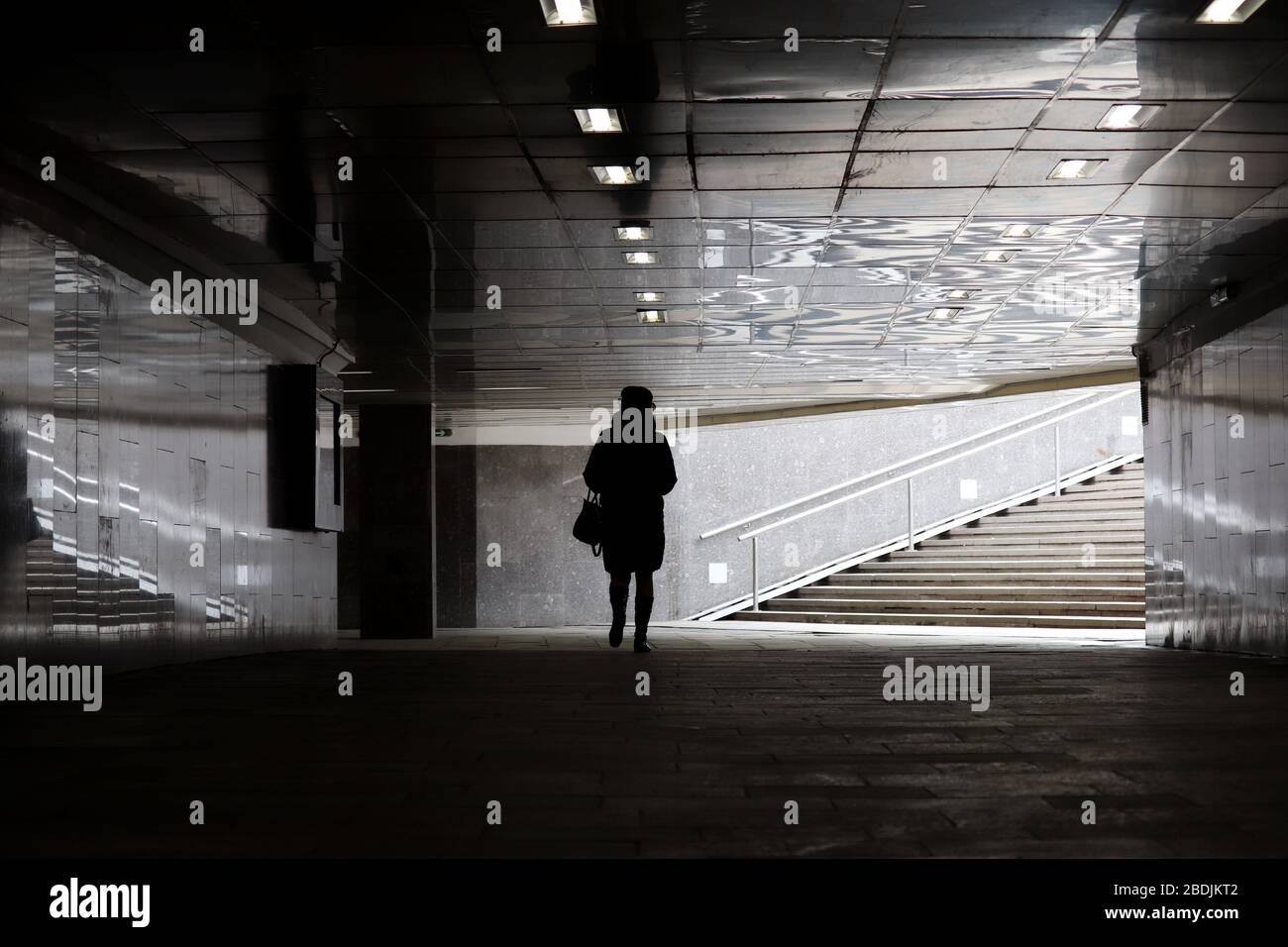 Quarantaine dans la ville pendant la pandémie de coronavirus du Covid-19. Silhouette de femme marchant dans un passage inférieur vide à Moscou Banque D'Images