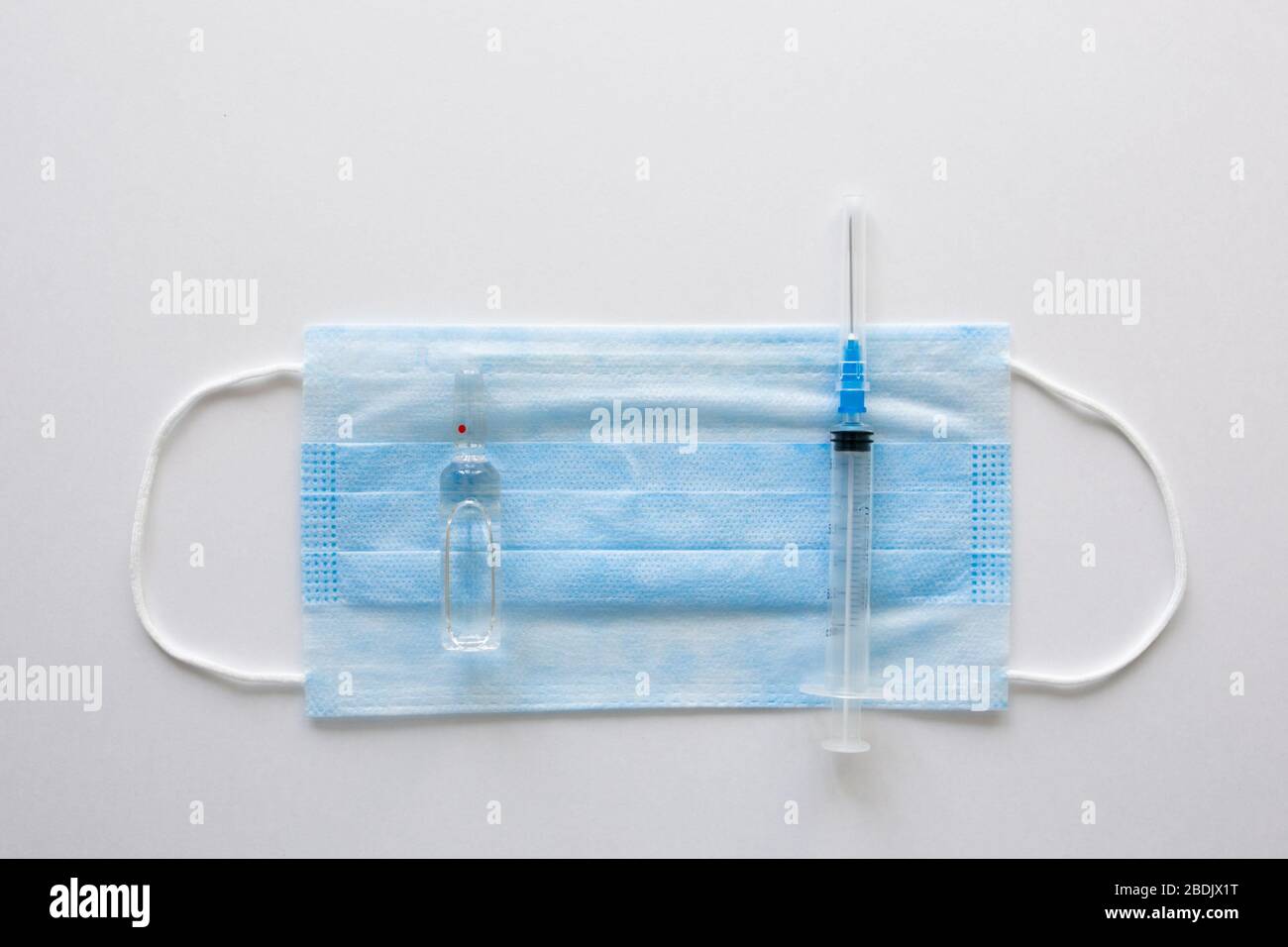 Masque médical antiviral pour la protection contre COVID-19. Bandage respiratoire médical visage sur fond blanc avec seringue. Banque D'Images