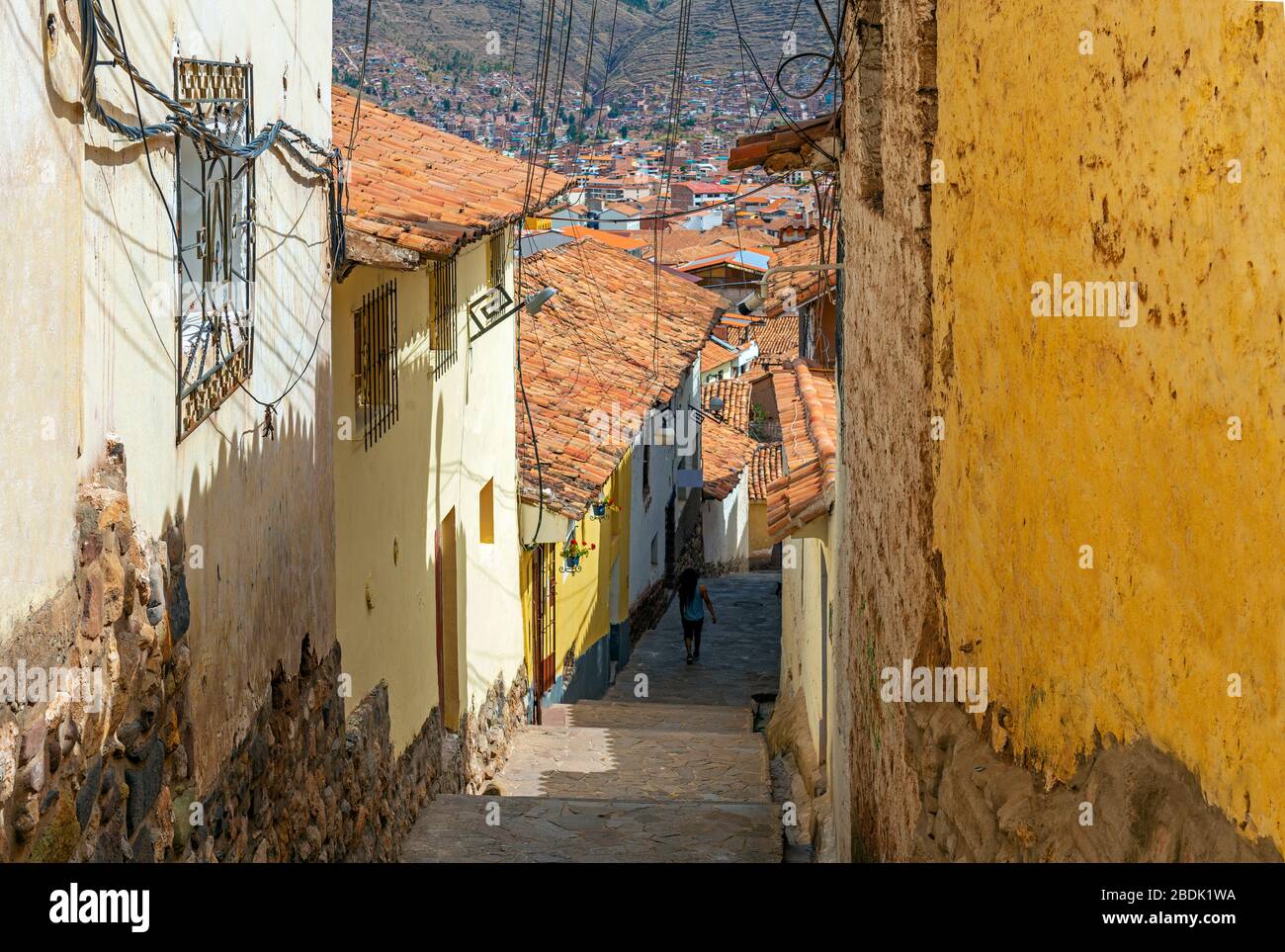 Une rue traditionnelle de style colonial dans le quartier de San Blas de Cusco avec une personne non reconnaissable marchant dans les escaliers, province de Cusco, Pérou. Banque D'Images