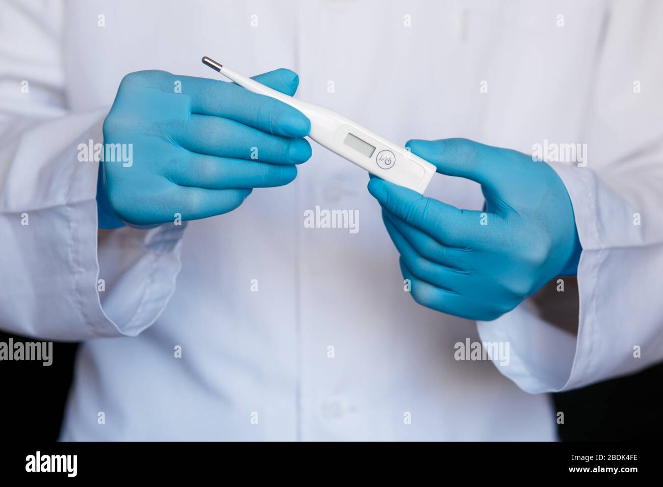 Gants de médecin masculin montrant le thermomètre. Médecin avec thermomètre dans les mains. Gros plan du thermomètre. Vie saine, docteur, concept de virus. Banque D'Images