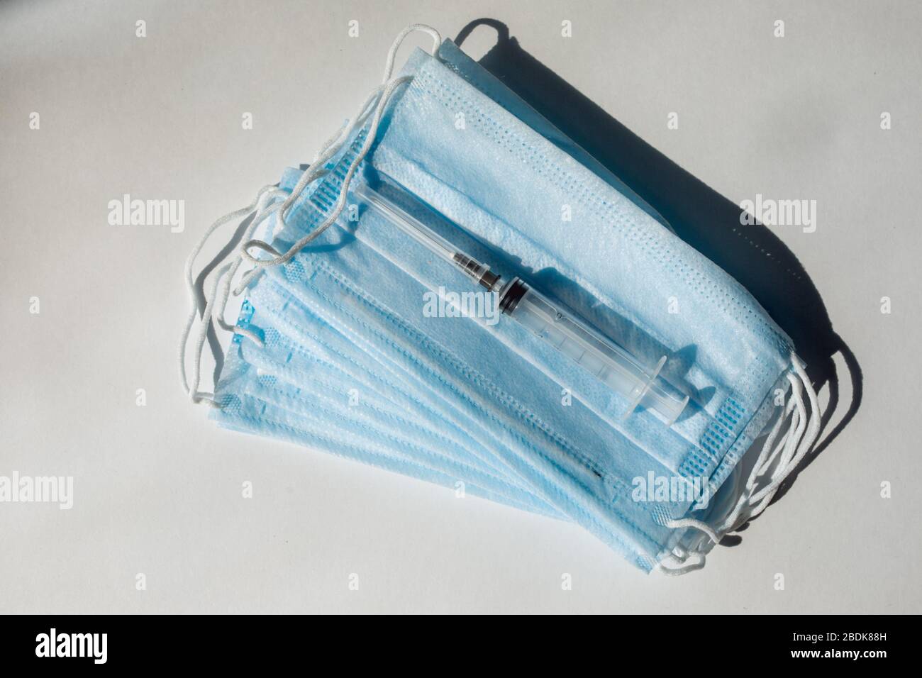 Seringue avec vaccin bleu et ampoule sur le masque médical. Fond blanc Banque D'Images