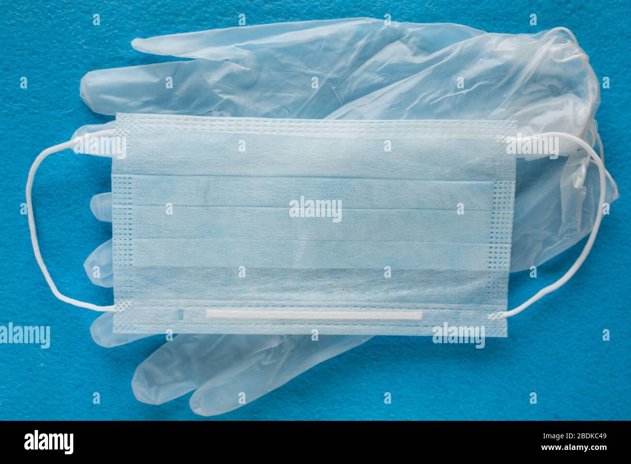 Une paire de gants en latex médical bleu fin et un écran facial sur fond blanc. Gants médicaux jetables en caoutchouc et masque. Sujets de protection. Recours. Banque D'Images