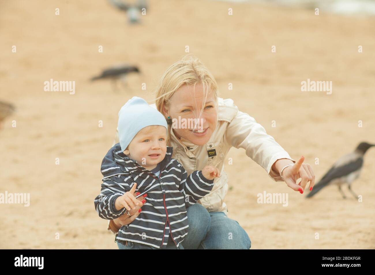 Une mère avec de longs cheveux maintient doucement son petit fils dans ses bras. Photo dans le parc avec lumière naturelle Banque D'Images