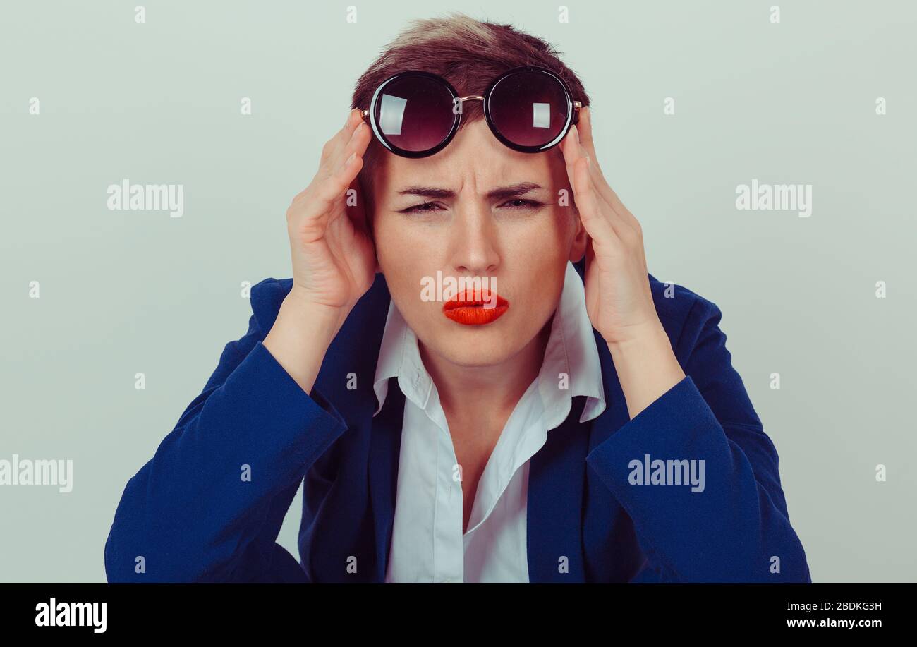 Headshot sérieuse femme en colère bas tenant des lunettes de soleil vers le haut sceptique regardant vous isolé mur vert fond bleu costume blanc chemise. Humain Banque D'Images