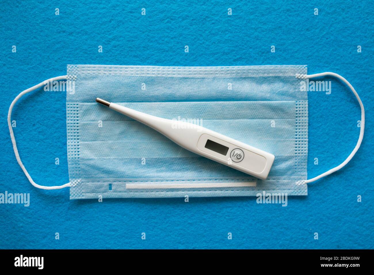 Masque médical pour la protection contre le coronavirus. Le masque de protection chirurgical et le thermomètre servant à mesurer la température se trouvent sur le masque médical. Bandage respiratoire médical pour le visage. Banque D'Images