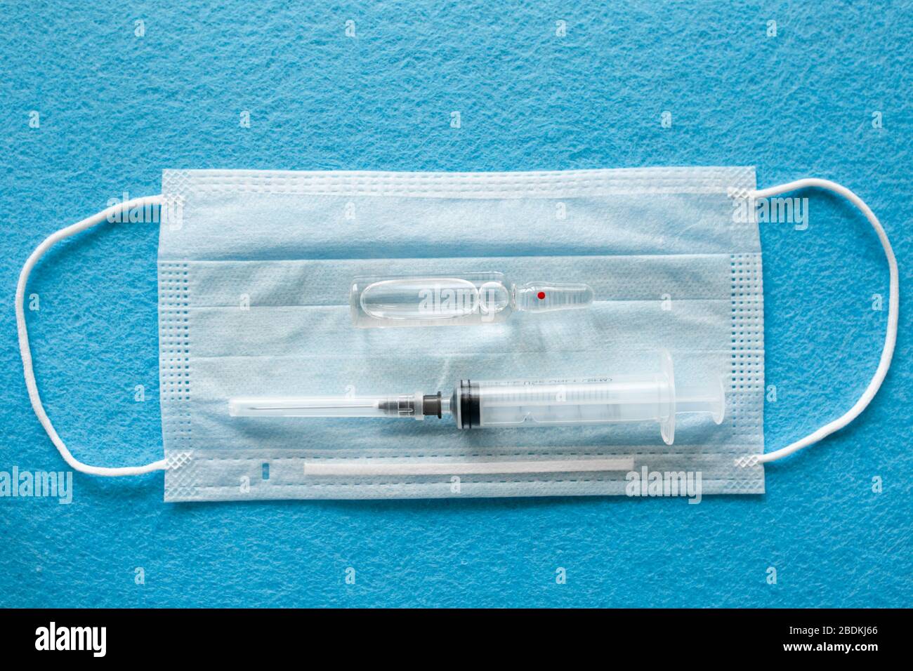 Masque médical antiviral pour la protection contre COVID-19. Bandage respiratoire médical visage sur fond blanc avec seringue. Banque D'Images