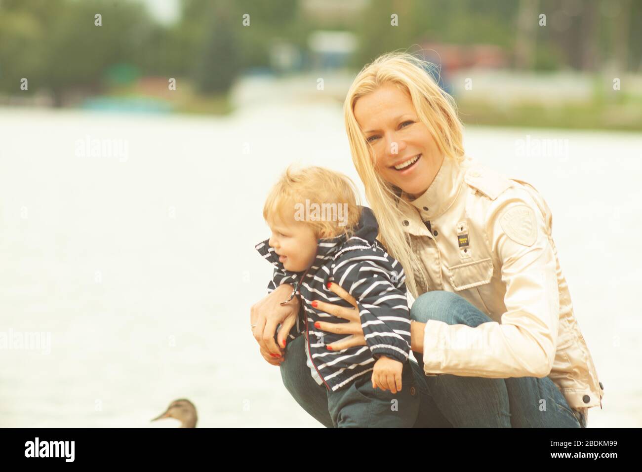 Une mère avec de longs cheveux maintient doucement son petit fils dans ses bras. Photo dans le parc avec lumière naturelle Banque D'Images